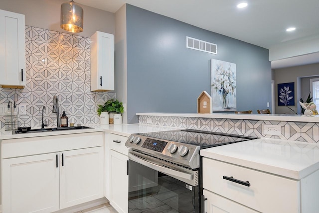 kitchen featuring tasteful backsplash, visible vents, a sink, light countertops, and stainless steel range with electric cooktop