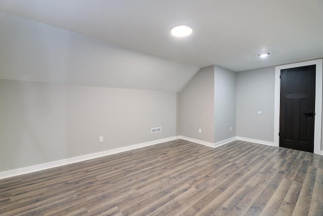 bonus room with dark wood-type flooring, baseboards, vaulted ceiling, and visible vents