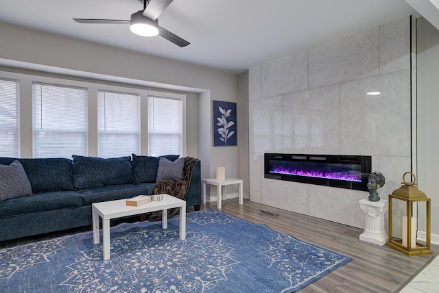 living room with wood finished floors, a large fireplace, and a ceiling fan
