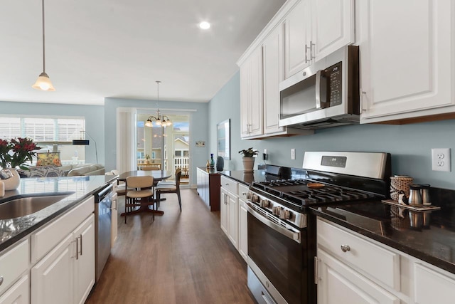 kitchen with a notable chandelier, dark wood finished floors, white cabinetry, stainless steel appliances, and pendant lighting