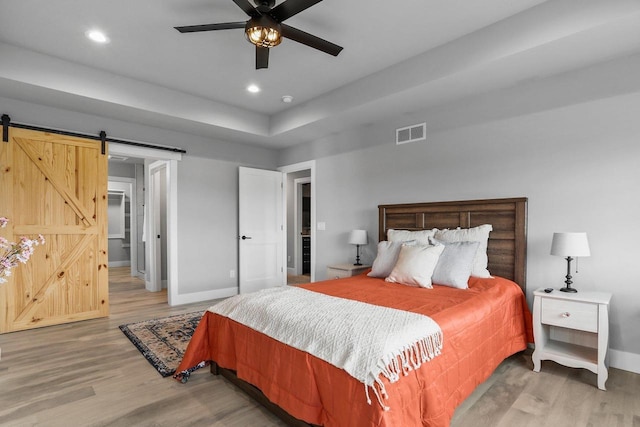 3102 Hope St, Sun Prairie, WI 53590 - bedroom featuring wood finished floors, baseboards, visible vents, and a barn door