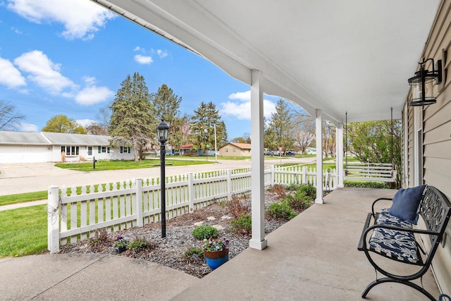 view of patio featuring a porch, fence, and a residential view