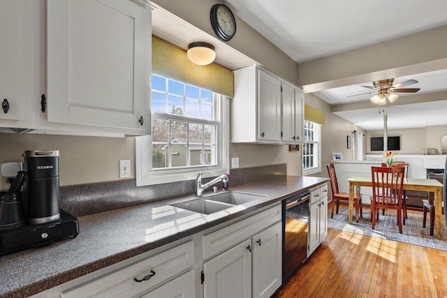 kitchen featuring plenty of natural light, a sink, black dishwasher, and dark countertops