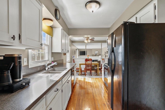 kitchen with a sink, black refrigerator with ice dispenser, white cabinets, and ceiling fan