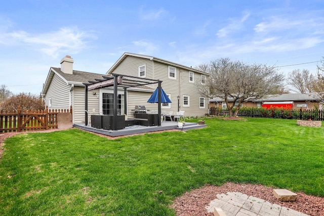 rear view of house with a chimney, a deck, a fenced backyard, an outdoor hangout area, and a yard