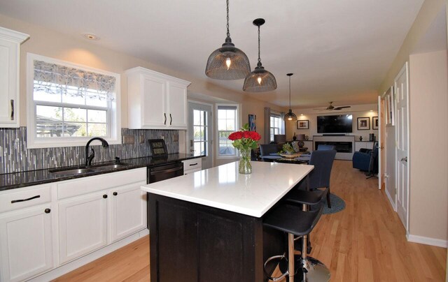 kitchen with white cabinets, a sink, a center island, open floor plan, and tasteful backsplash