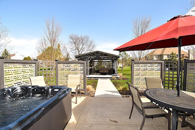 view of patio with a gazebo, a hot tub, fence, and outdoor dining space