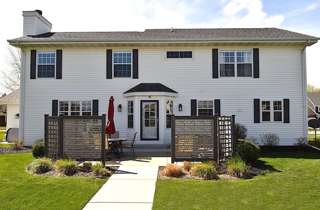 colonial home with a patio, a chimney, and a front yard