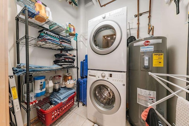 washroom featuring stacked washer and dryer, electric water heater, tile patterned flooring, and laundry area