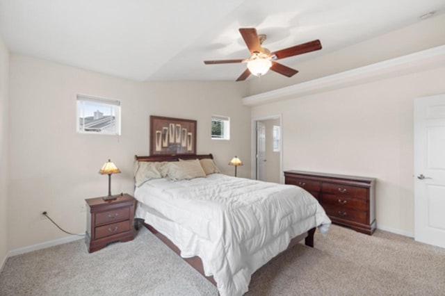 bedroom featuring light carpet, ceiling fan, baseboards, and vaulted ceiling