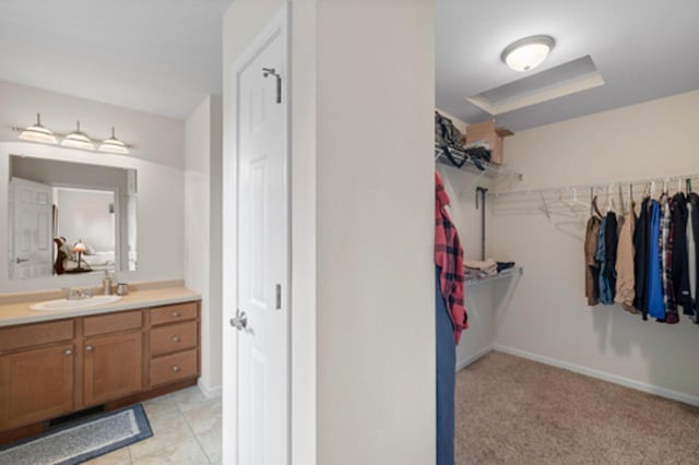 interior space with a walk in closet, vanity, and baseboards
