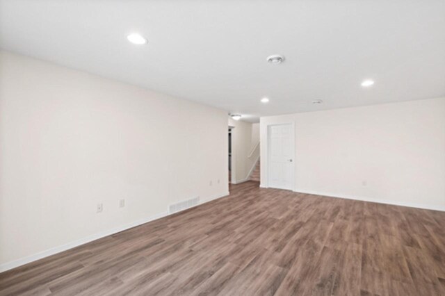 empty room featuring wood finished floors, recessed lighting, visible vents, and stairs
