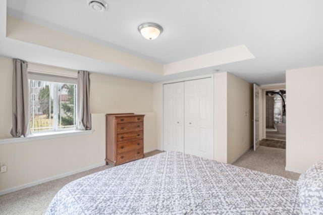 bedroom with a raised ceiling, a closet, baseboards, and carpet floors