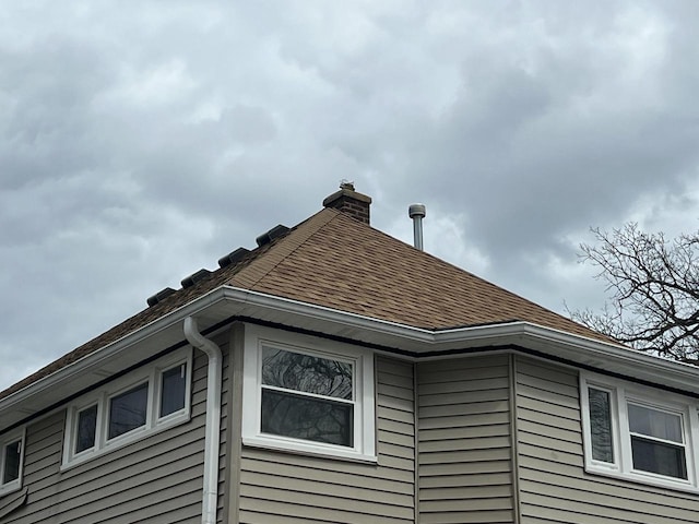 view of home's exterior with a shingled roof and a chimney