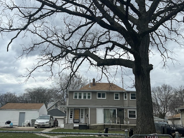 view of front of home with a front yard, an outdoor structure, and a chimney