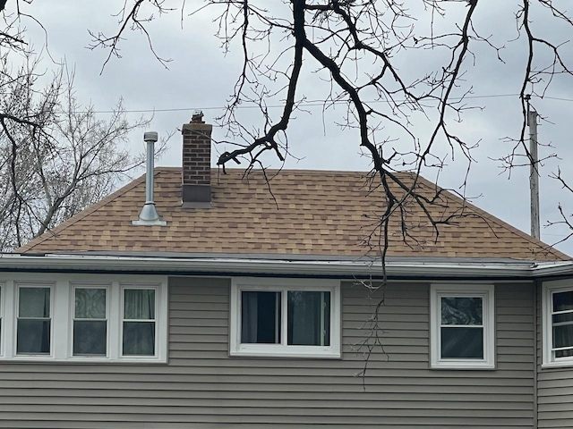 view of property exterior with roof with shingles and a chimney