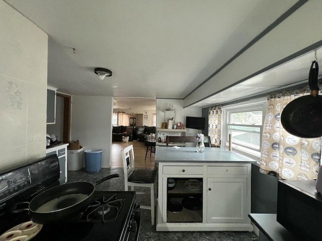 kitchen featuring black range with gas stovetop and white cabinetry