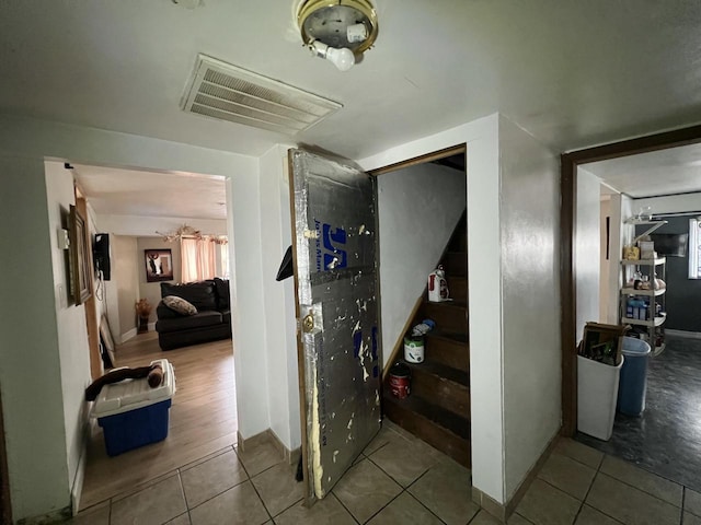 hall with tile patterned floors, baseboards, visible vents, and stairs