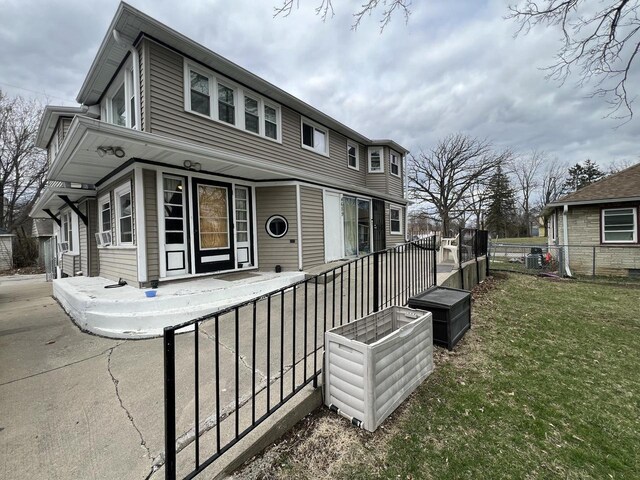 view of front of home featuring cooling unit, fence, and a front lawn