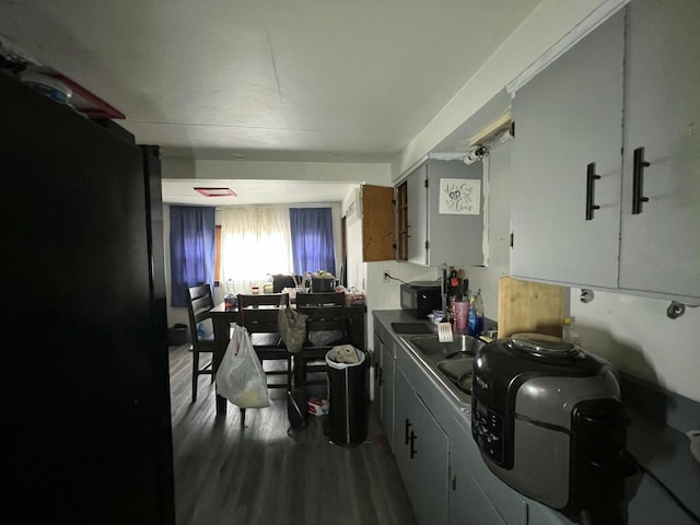 kitchen with dark countertops, black microwave, and wood finished floors