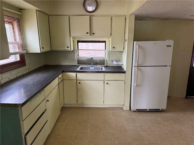 W5588 US Highway 8, Tony, WI 54563 - kitchen with cream cabinets, freestanding refrigerator, dark countertops, decorative backsplash, and a sink