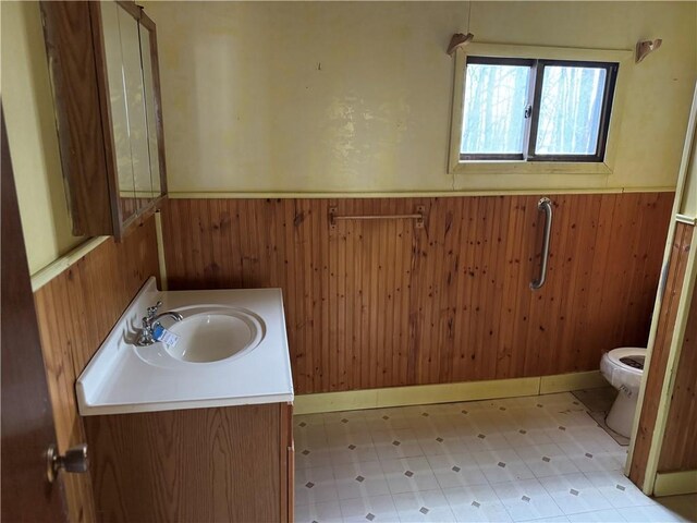 W5588 US Highway 8, Tony, WI 54563 - bathroom with wood walls, toilet, vanity, and a wainscoted wall
