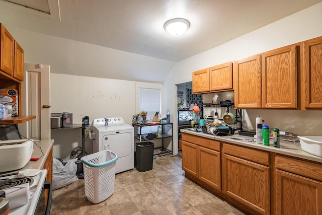kitchen featuring brown cabinets, light countertops, washer / dryer, and lofted ceiling