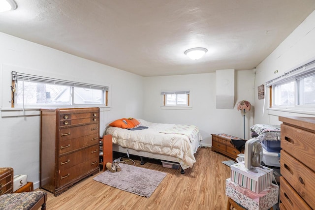 bedroom with light wood-type flooring, baseboards, and multiple windows