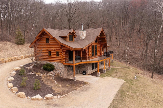 N8070 Wanlass Rd, Mindoro, WI 54644 - view of front of house with log exterior, a deck, stone siding, dirt driveway, and a view of trees