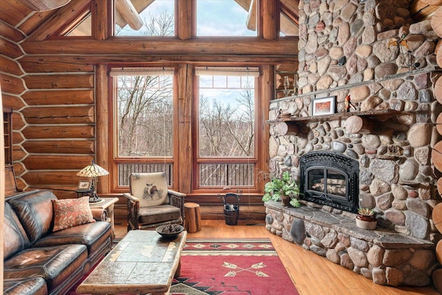 N8070 Wanlass Rd, Mindoro, WI 54644 - living room featuring log walls, a stone fireplace, hardwood / wood-style flooring, and lofted ceiling
