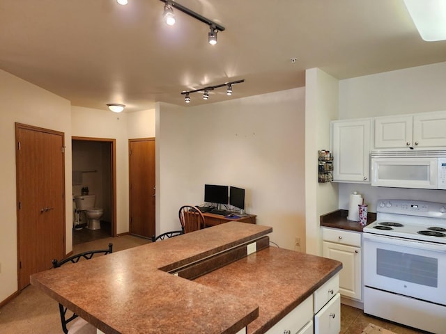 kitchen featuring white cabinets, dark countertops, white appliances, and a kitchen island