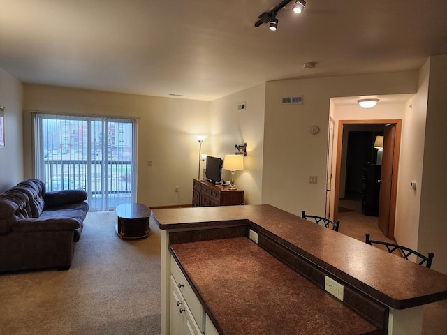 kitchen featuring open floor plan, white cabinetry, carpet floors, dark countertops, and visible vents