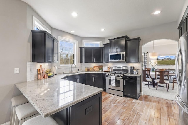 W246N1979 Still River Dr, Pewaukee, WI 53072 - kitchen featuring a sink, a kitchen breakfast bar, a peninsula, stainless steel appliances, and light stone counters