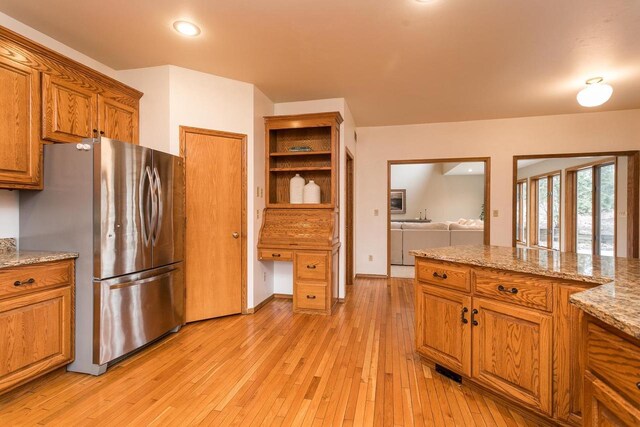 4510 Choctaw Trl, Green Bay, WI 54313 - kitchen with recessed lighting, freestanding refrigerator, light stone countertops, brown cabinets, and light wood finished floors