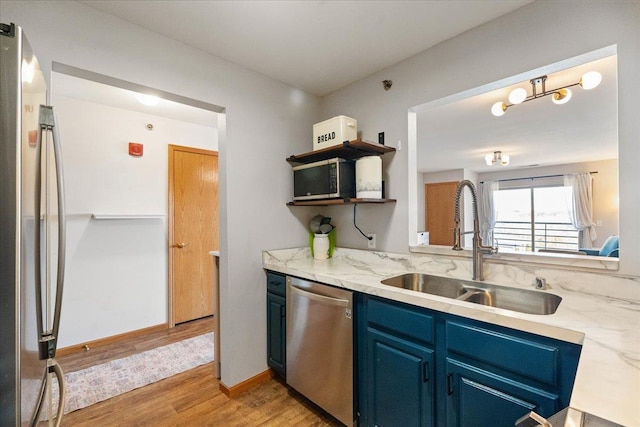 kitchen featuring open shelves, blue cabinets, a sink, light wood-style floors, and appliances with stainless steel finishes