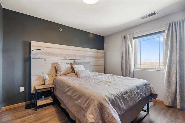 bedroom with baseboards, wood finished floors, and visible vents
