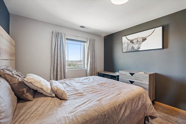 bedroom with baseboards, wood finished floors, and visible vents