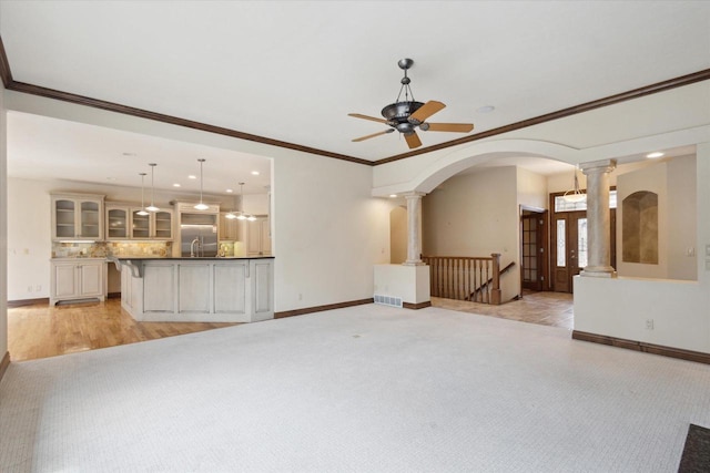 1716 Symphony Hts, Green Bay, WI 54311 - unfurnished living room with ornate columns, ceiling fan, baseboards, and arched walkways