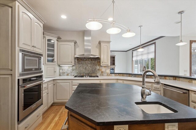 1716 Symphony Hts, Green Bay, WI 54311 - kitchen with a kitchen island with sink, light wood-style floors, wall chimney exhaust hood, decorative backsplash, and stainless steel appliances