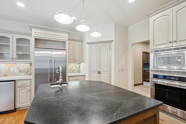 1716 Symphony Hts, Green Bay, WI 54311 - kitchen with decorative backsplash, a center island with sink, built in appliances, and pendant lighting