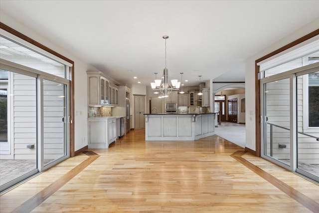 1716 Symphony Hts, Green Bay, WI 54311 - kitchen with glass insert cabinets, arched walkways, an inviting chandelier, a kitchen bar, and stainless steel microwave
