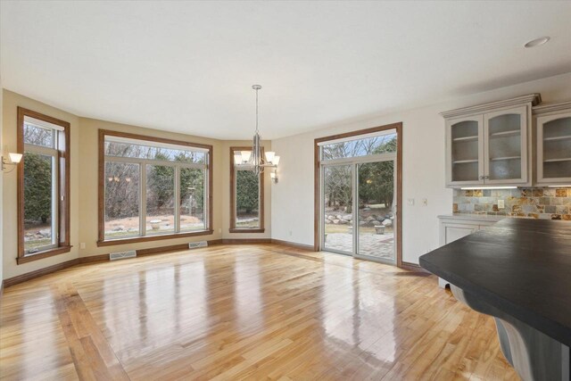 1716 Symphony Hts, Green Bay, WI 54311 - unfurnished dining area with a chandelier, visible vents, light wood-type flooring, and baseboards