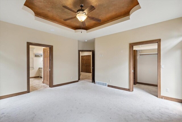 1716 Symphony Hts, Green Bay, WI 54311 - unfurnished bedroom with a walk in closet, visible vents, a tray ceiling, and light colored carpet