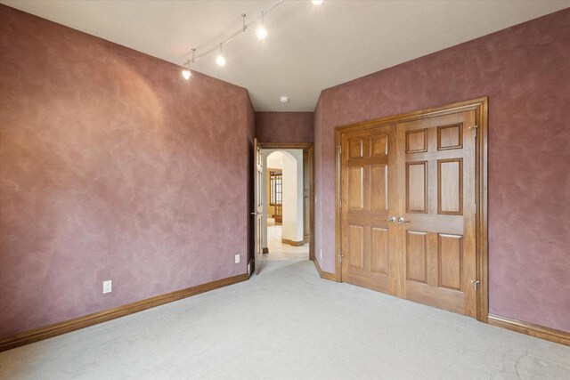 1716 Symphony Hts, Green Bay, WI 54311 - unfurnished bedroom featuring rail lighting, arched walkways, a closet, carpet floors, and baseboards