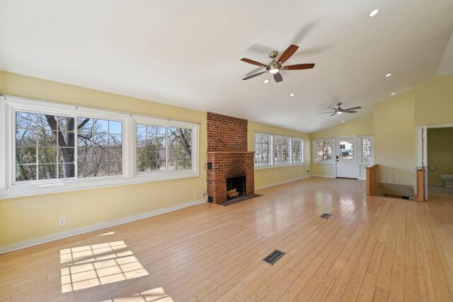 149 Oakwood Ave, Edgerton, WI 53534 - unfurnished living room featuring light wood-type flooring, a brick fireplace, vaulted ceiling, and a ceiling fan
