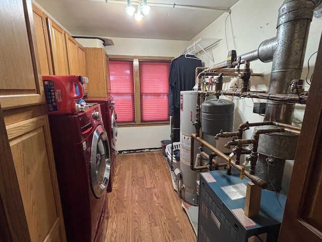 clothes washing area with water heater, wood finished floors, separate washer and dryer, and cabinet space