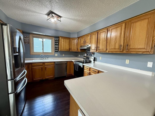 1411 Jennifer Ave, Tomah, WI 54660 - kitchen featuring a sink, a textured ceiling, brown cabinets, under cabinet range hood, and stainless steel appliances