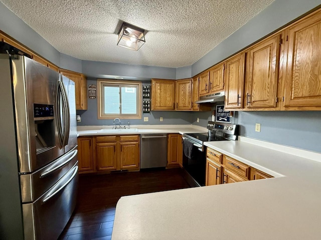 1411 Jennifer Ave, Tomah, WI 54660 - kitchen with dark wood-type flooring, a textured ceiling, appliances with stainless steel finishes, under cabinet range hood, and a sink