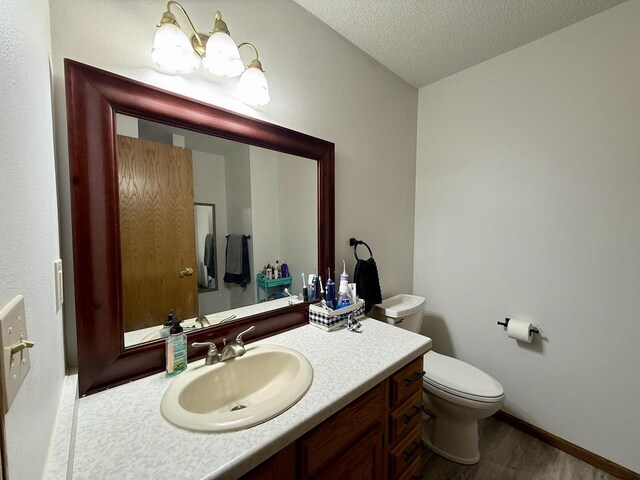 1411 Jennifer Ave, Tomah, WI 54660 - bathroom with vanity, baseboards, a textured ceiling, toilet, and wood finished floors