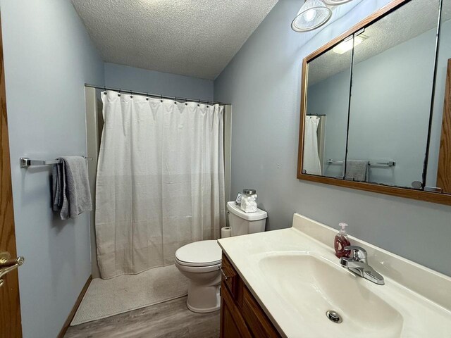 1411 Jennifer Ave, Tomah, WI 54660 - full bathroom with curtained shower, toilet, a textured ceiling, vanity, and wood finished floors